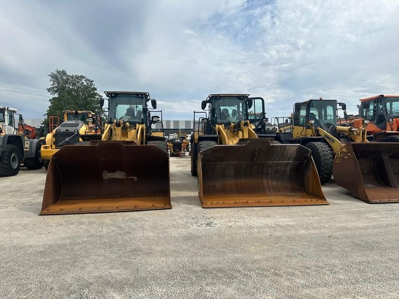 Row of used Caterpillar, Komatsu and Doosan wheel loaders in a European equipment yard