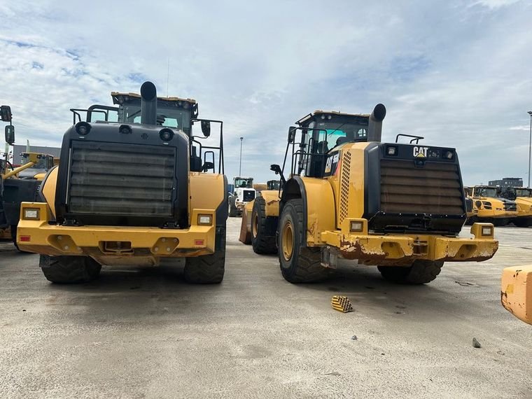 Two Caterpillar 966M wheel loaders parked side by side in the trading yard